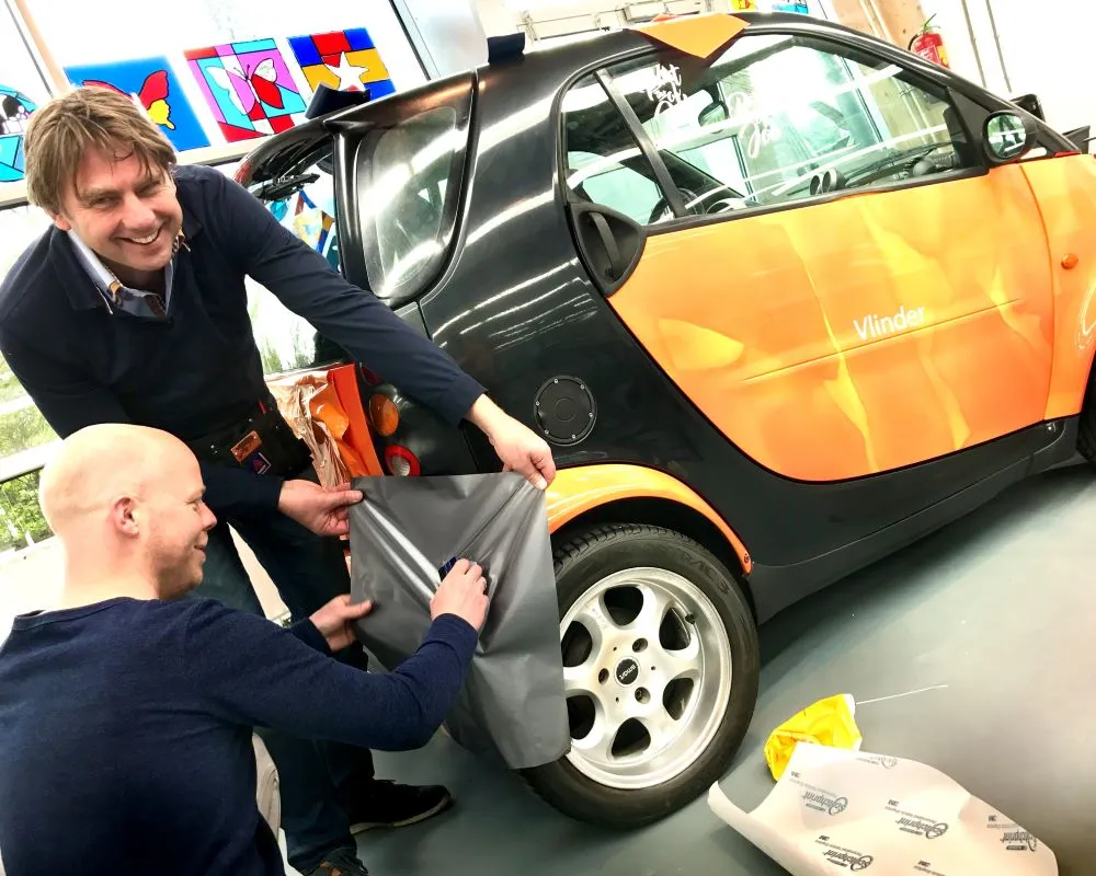 Docent van MBO en Appcademy trainer wrappen op een spatbord tijdens Appcademy workshop en gastcollege op ROC / MBO opleiding signmaker