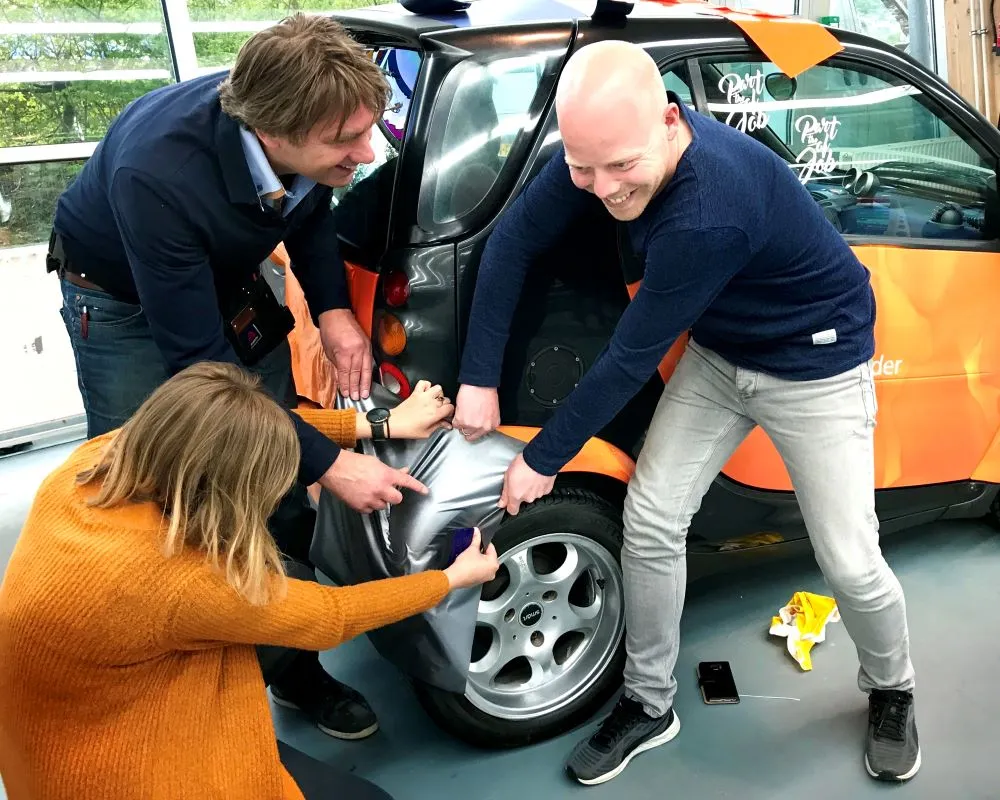 2 docenten en 1 trainer wrappen op een spatbord tijdens Appcademy workshop en gastcollege op ROC / MBO opleiding signmaker