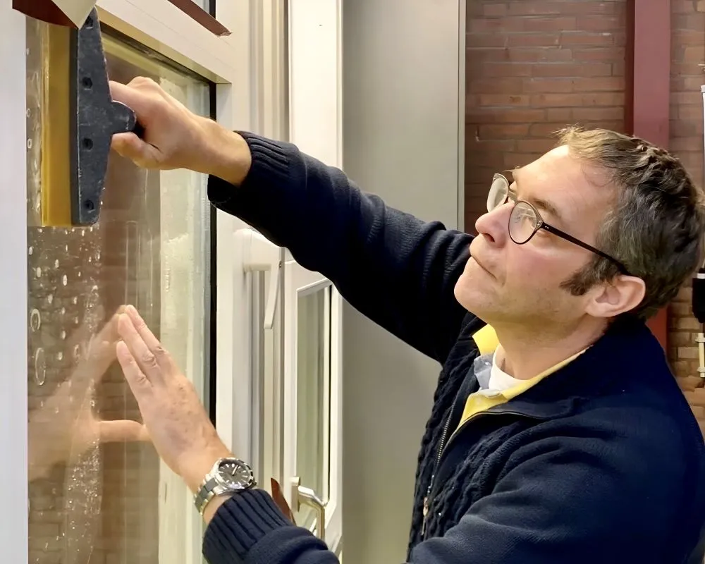 Trainer drukt raamfolie aan met een rakel op glaswerk als demo tijdens Appcademy Architectural Windowfilm training
