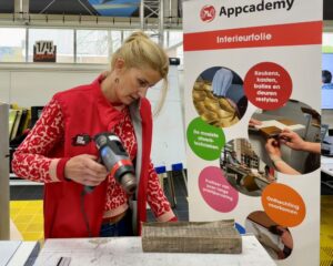 Cursist wrapt met interieurfolie op een keuken paneel als praktijkoefening tijdens de Appcademy training kitchen wrap