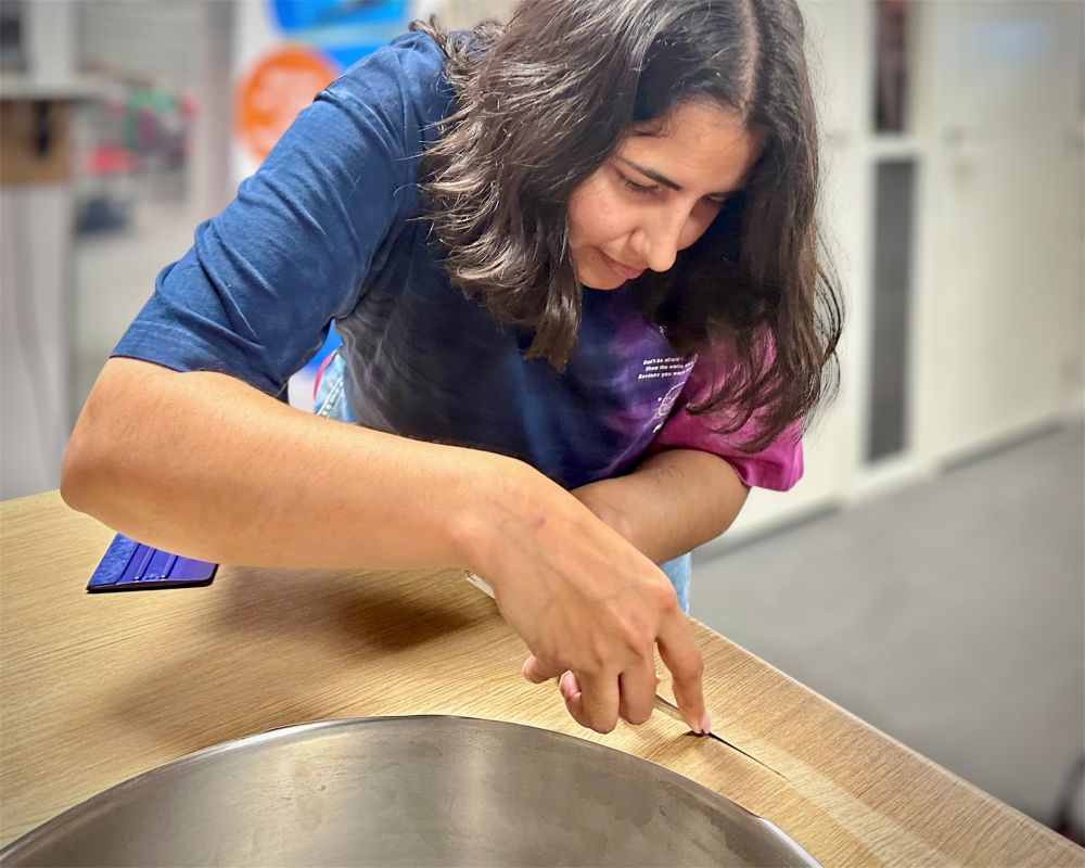 cursist brengt meubelfolie aan op een aanrechtblad rond de spoelbak tijdens de Appcademy Interieurfolie cursus: Keukens Wrappen van A-Z