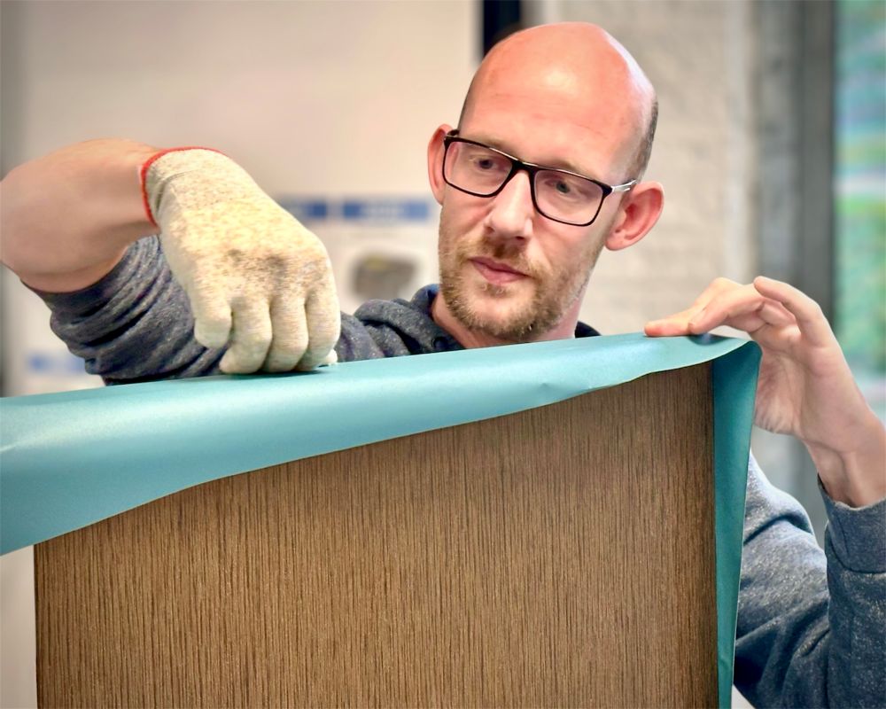 Cursist werkt interieurfolie technisch juist af op een keukenkast frontje of ladefront als praktijkoefening tijdens de Appcademy training keukens wrappen