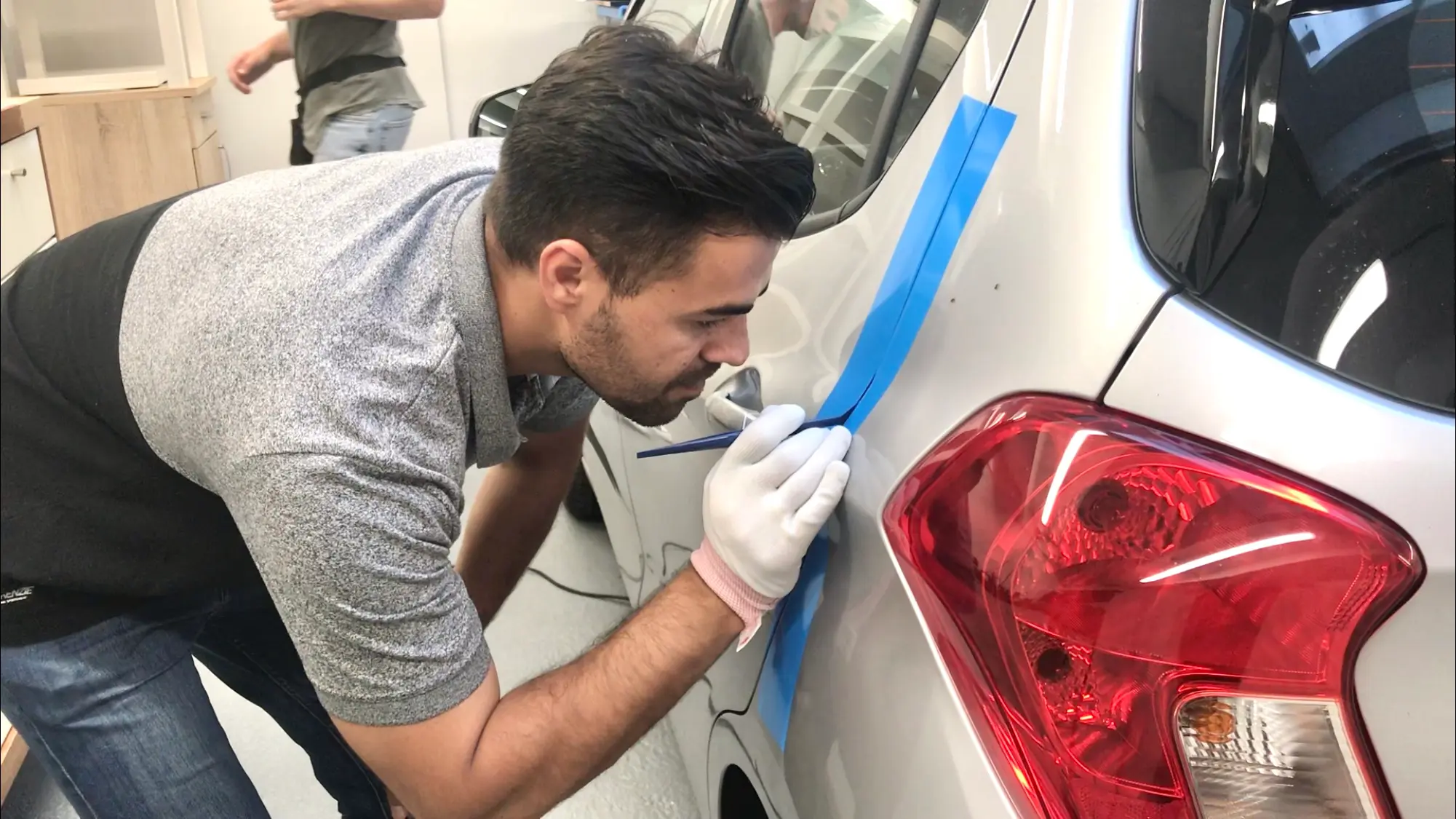 man snijdt carwrapfolie bij portiernaad