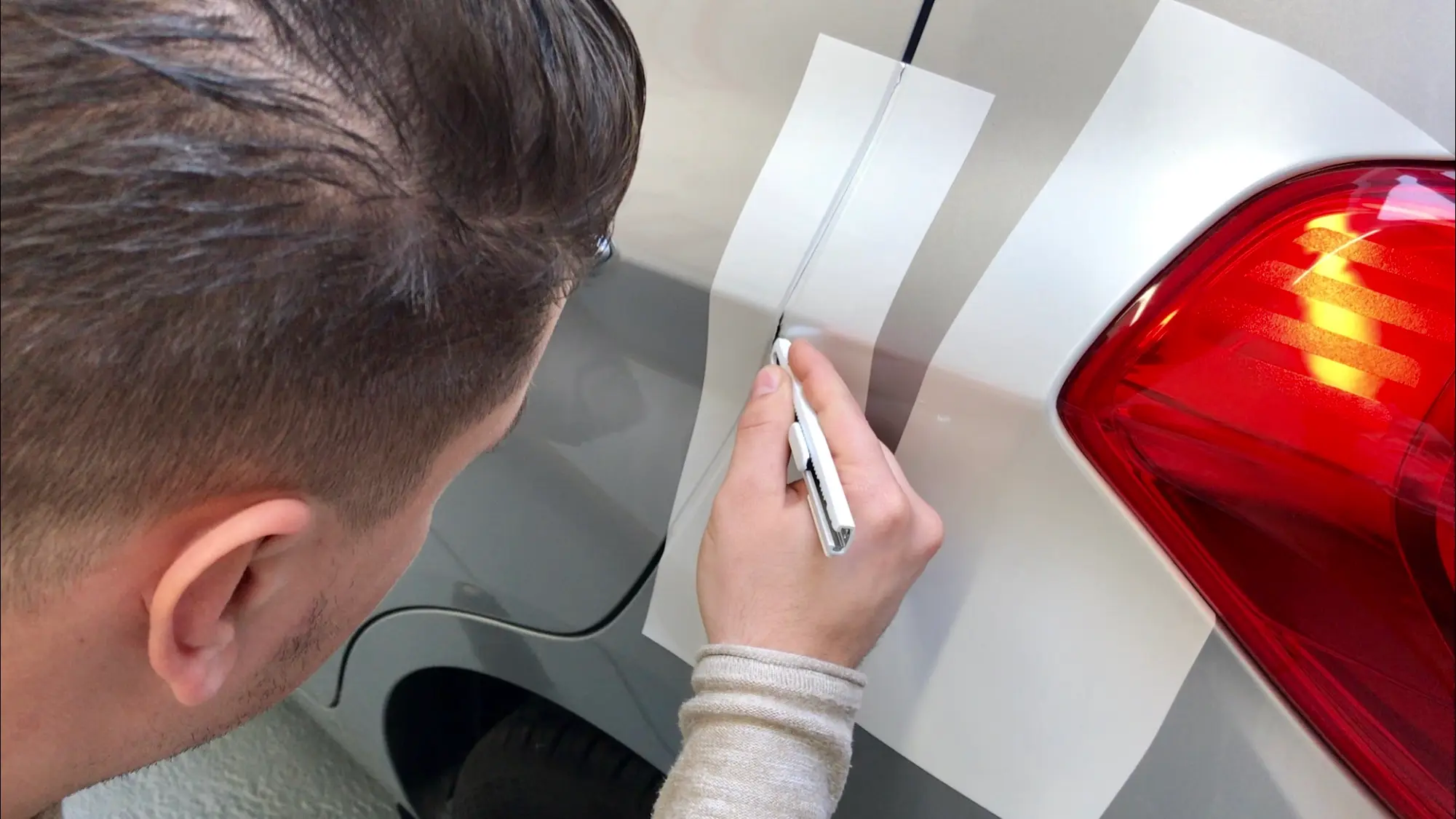 man snijdt carwrapfolie bij portiernaad