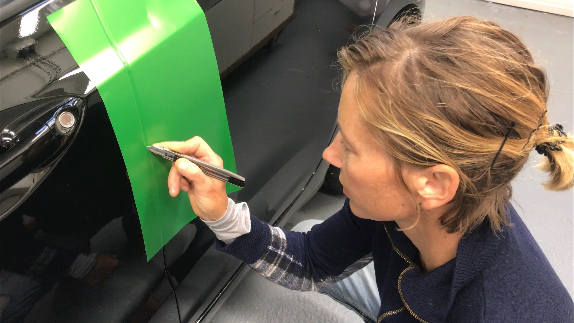vrouw snijdt folie bij portiernaad bij Appcademy training carwrap